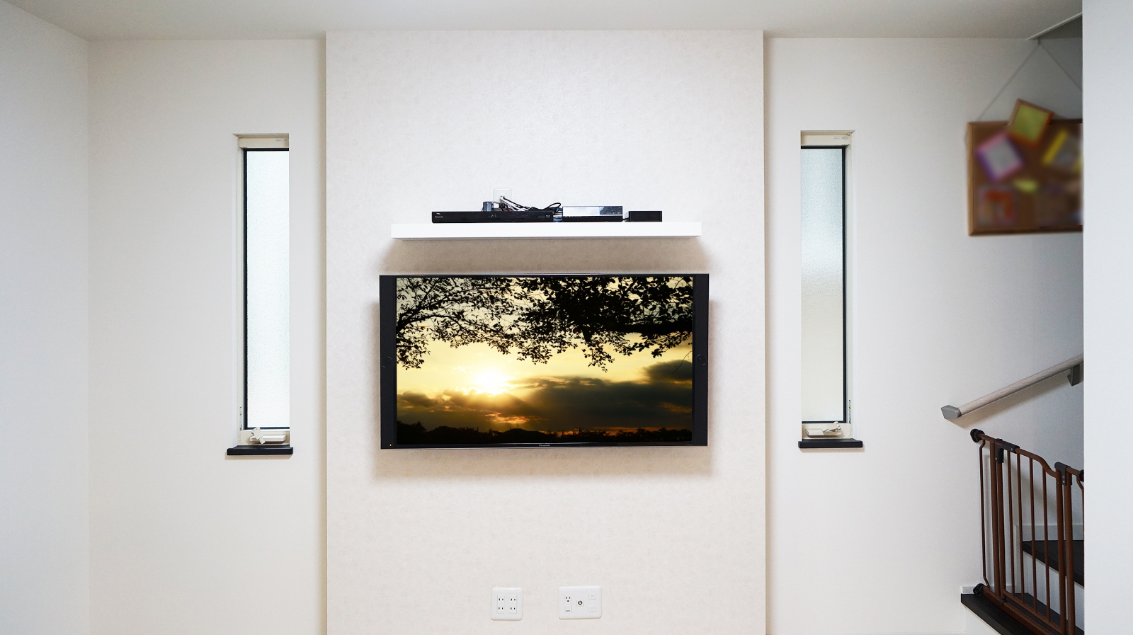 リビングのふかし壁に49インチ・液晶テレビ「TH-49EX850」と周辺機器専用シェルフの壁掛け施工をさせていただきました。

「ふかし壁はデザイン性にも美しく、オシャレな壁面を演出できる点にもこだわりました」とオーナー様よりお伺い致しました。
将来的には壁掛けテレビでよりこだわりの空間を構想されていて、補強下地も施工済みでしたので、「今回ようやく念願叶いました」と仰っておられました。

キッカケとして大きかった事は、テレビ台を無くす事による掃除のしやすさ、お子さんが大きくなる中でテレビ台に置いたテレビの転倒(接触や地震による)が心配になった事だとお聞きしました。

シェルフ位置もお子さんの手の届かない場所をイメージされてテレビ上側にこだわられた事で、テレビ下スペースをとてもスッキリとすることが出来ました。
掃除機の掛けやすさは大幅に向上し、お子さんの遊べるスペースも増えた事にも大変喜んで頂く事ができました。

壁掛け金具には、キッチン・ダイニング・リビングのどこからでも楽々視聴できるように上下左右可動式金具をご選択されました。

今回のテレビは両側にスピーカーを搭載し、テレビ背面形状が特徴的なモデルでしたので、オーナー様からは壁掛け金具についても事前にご相談を受けておりましたが、過去にも施工経験がございますので、将来的にテレビを買い替えられた際にも引き続きお使い頂ける金具をご選定させていただきました。

構想されていた壁掛けテレビの実現と合わせて、シェルフや金具のイメージ以上の使い勝手の良さにオーナー様には大変満足していただけました。