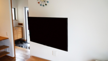 白がとても美しく明るいリビングに、43インチ・ブラビア「KJ-43X7500F」を壁掛け施工させていただきました。

壁掛け施工に合わせまして、テレビの同時購入もご用命頂きました。
ご依頼のキッカケは今まで使われていたテレビの調子が悪くなり買い替える際に、新しいテレビを壁掛けにしようと思われたそうです。

壁には補強下地があり、コンセントも通常よりも少し高い位置に設置されていました。
既存のコンセント位置は、将来的にテレビサイズが大きくなることを想定すると、壁掛けテレビ的には低い位置でしたので、そのまま残して壁掛けテレビ用に1か所新設させていただきました。

壁掛け金具には、上下左右可動式金具を用いる事で、キッチンやダイニングからの視聴にも適した角度調整が可能です。

オーナー様からは今までテレビスタンドが固定されていた為に、ダイニングやキッチンから見えにくい事も事前にご相談を受けていましたので、施工後の金具が可動した際には、イメージ以上の快適さに大変満足していただけました。

ダイニング用にもう1台壁掛け予定でしたが、可動できる金具により必要が無くなった事も大きなメリットになり、とても喜んで頂く事ができました。

